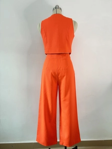Close-up of bright orange sleeveless crop top and high-waisted wide-leg trousers set