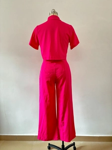 Vue arrière d'un ensemble deux pièces rose vif avec chemise à manches courtes et pantalon large