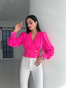 Detail of bright pink V-neck shirt showing pleated bust and gold button waist