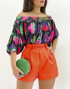 Detail of off-shoulder heart print top paired with orange shorts and woven belt