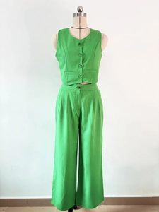 Detailed close-up of green linen-textured sleeveless vest and high-waisted wide-leg trousers