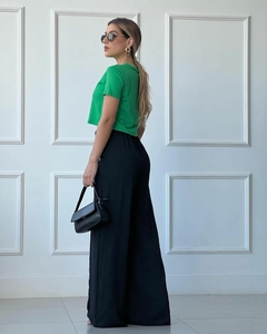 Detail of high-waist pleated wide-leg trousers paired with a green cropped t-shirt