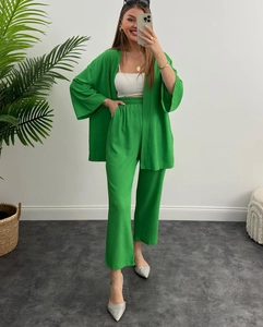 Dettaglio del set due pezzi verde smeraldo con pantaloni a vita alta e cardigan aperto