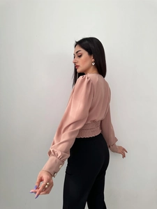 Detail of smocked waist design and puffed sleeves on this pink long sleeve shirt