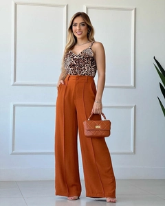 Detail of high-waisted orange wide-leg trousers with front pleats and leopard print camisole