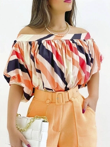 Detail of off-shoulder striped blouse with puff sleeves and high-waist orange trousers