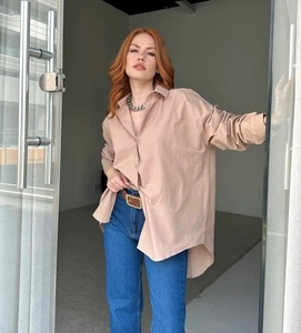 Detail view of khaki oversized long sleeve shirt paired with a leather belt and denim jeans