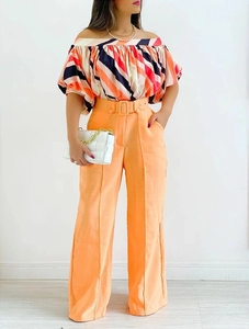 Detail of off-shoulder striped crop top and orange wide-leg trousers with belt