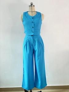 Detail der leuchtend blauen ärmellosen Weste mit Knöpfen und passender Hose mit hoher Taille