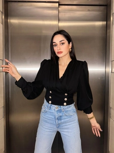 Detail of black V-neck puff sleeve blouse featuring elegant gold double-breasted buttons
