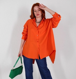 Detail of bright orange oversized long sleeve shirt with asymmetric split hem design