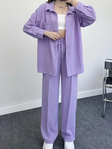 Detail of purple pleated two-piece set with long-sleeve shirt and wide-leg pants texture