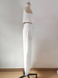 Side view detail of white sleeveless vest and wide leg trousers with pocket flaps