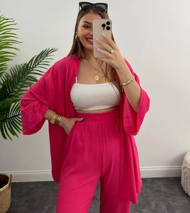 Dettaglio del set due pezzi rosa acceso plissettato con camicia a maniche lunghe e pantaloni