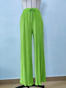 Detail view of the drawstring waist and pleated texture on lime green wide leg pants