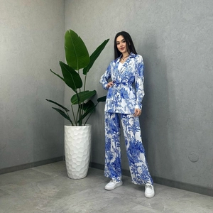 Detail of blue palm tree print on white long sleeve belted top and wide leg pants