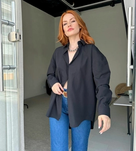 Detail of oversized black long sleeve shirt paired with blue jeans and chain necklace