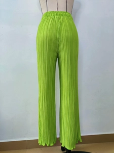 Detail view of bright green pleated wide-leg pants featuring elastic waist with drawstrings