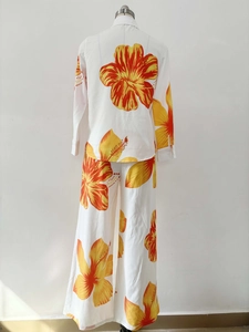 Rear view of white two-piece set featuring tropical orange hibiscus floral print pants