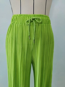 Detail of green plisse pants showing elastic drawstring waist with metal tips