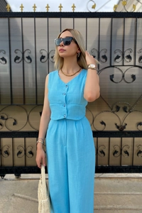 Detail of light blue two-piece linen set with V-neck buttoned vest and wide leg pants