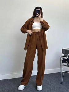 Detail of high-waist brown wide-leg trousers with drawstring waist and textured fabric