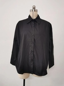 Detail of the classic lapel collar and single-breasted buttons on a black loose shirt