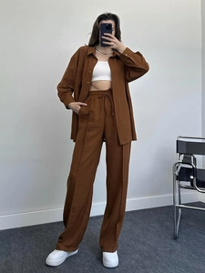 Detail of high-waisted wide-leg trousers with drawstring and pleated texture in dark brown