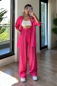 Full view of pink leopard print shirt and wide leg trousers set on a model in a bright room