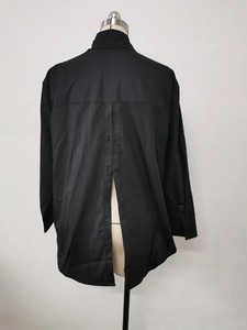 Detail of loose black shirt featuring a unique vertical back split with five buttons