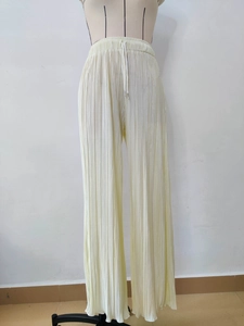 Detail of high-waist pleated wide-leg trousers with adjustable drawstring in light yellow