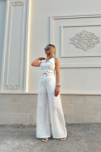 Detailed view of white sleeveless buttoned vest and matching wide-leg high-waisted trousers