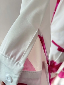 Detailed macro view of white sleeve cuff with pink floral prints and resin button