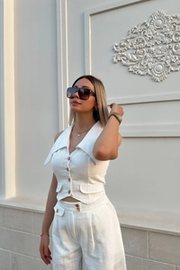 Detailed view of white linen sleeveless vest and high-waisted pants summer set