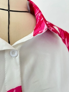 Detailed view of the white lapel shirt with pink tropical leaf print and white button