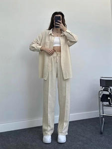 Detail of loose-fit beige linen shirt and matching drawstring wide-leg trousers for women