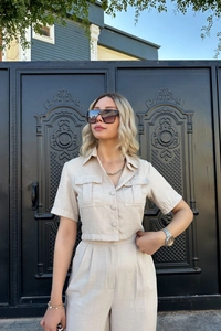 Détail d'un ensemble deux pièces en lin beige avec haut court boutonné et poches à rabat