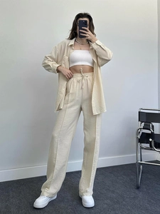 Detail of beige two-piece lounge set showing drawstring waist and pleated wide-leg pants