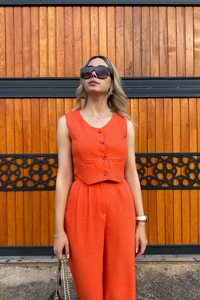 Detail shot of orange two-piece set featuring linen texture vest and wide-leg trousers