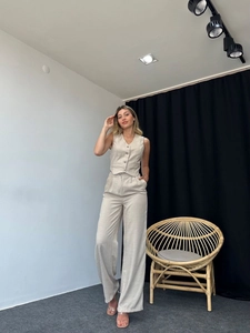 Detail of oat-colored vest and high-waist wide-leg trousers in textured fabric