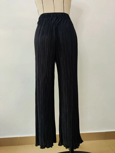 Detailed close-up of high-waisted black pleated wide-leg trousers on a mannequin