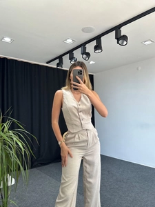 Detail of beige two-piece set featuring a v-neck vest and high-waisted wide-leg linen pants