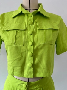 Detail of neon green short-sleeved shirt with flap pockets and fabric-wrapped buttons