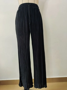 Detail of black pleated wide-leg trousers featuring elastic drawstring waist and smooth texture