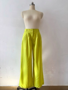 Detail of high-waisted fluorescent green wide-leg trousers with front pleat accents