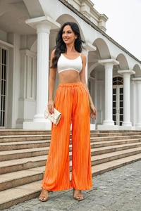 Macro view of bright orange pleated wide-leg pants showing texture and high waist detail