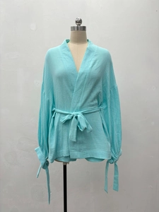Détail d'un haut kimono bleu clair avec texture froissée et nœuds aux manches