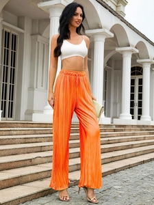 Detail of orange pleated wide-leg trousers featuring drawstring waist and flowing fabric