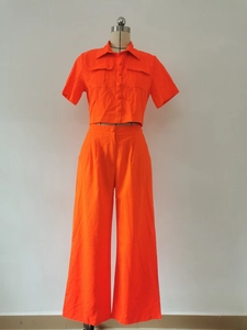 Detail of bright orange short sleeve shirt with flap pockets and wide leg high waist pants