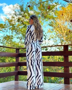 Detail view of the zebra print blouse and high-waist trousers on a sunny wooden terrace